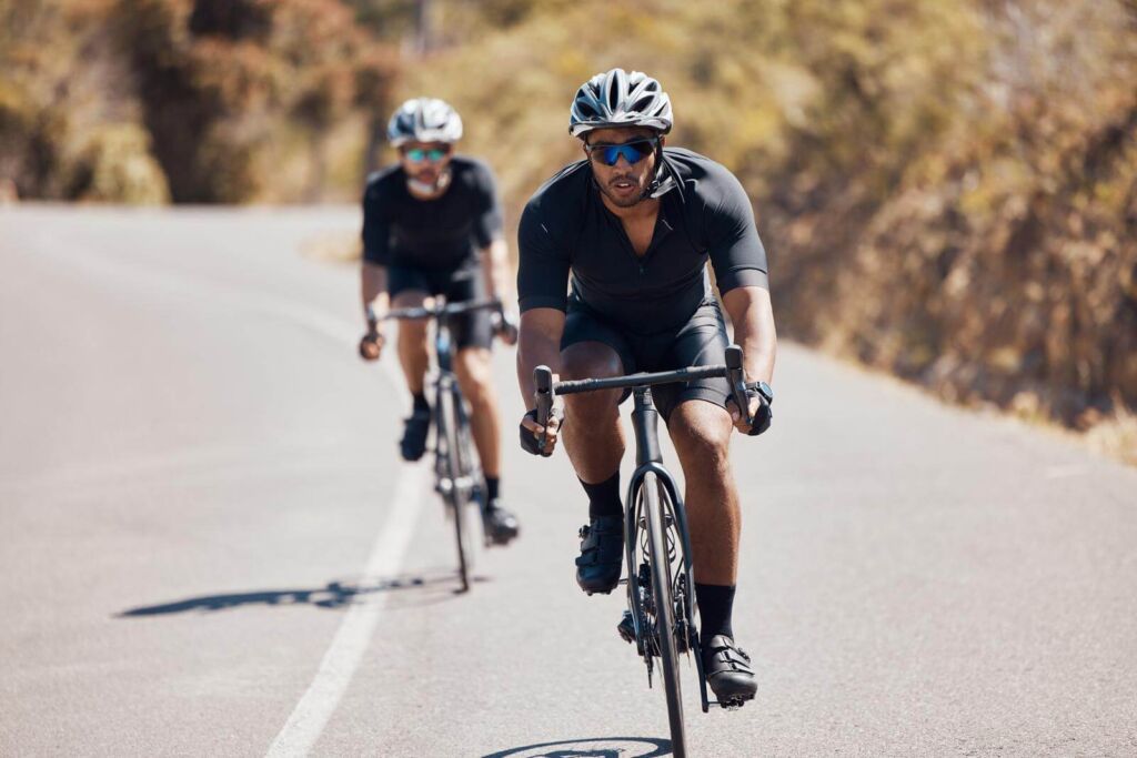 Fitness man cycling bike on mountain road for cardio exercise