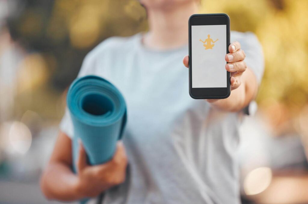 A girl holding a mat and a cellphone